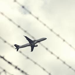 Startendes Flugzeug durch einen Zaun fotografiert
