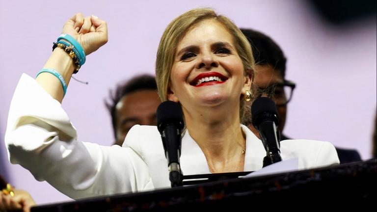 Laura Fernández reckt während einer Rede triumphierend die Faust in die Höhe.