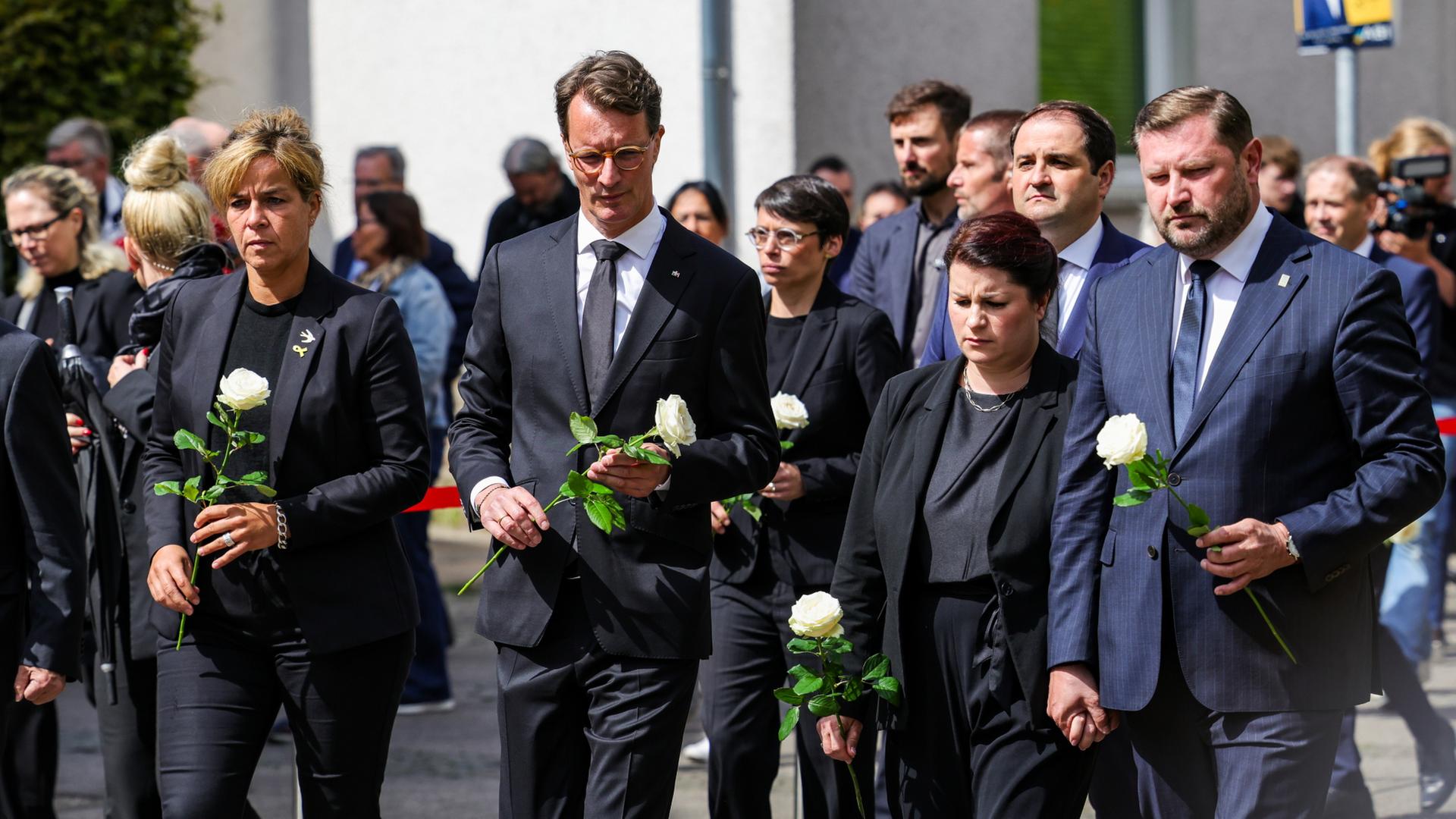 Ministerpräsident Wüst und andere Politikerinnen und Politiker halten bei der Gedenkfeier für die Anschlagsopfer von Solingen Rosen in der Hand.  | dpa