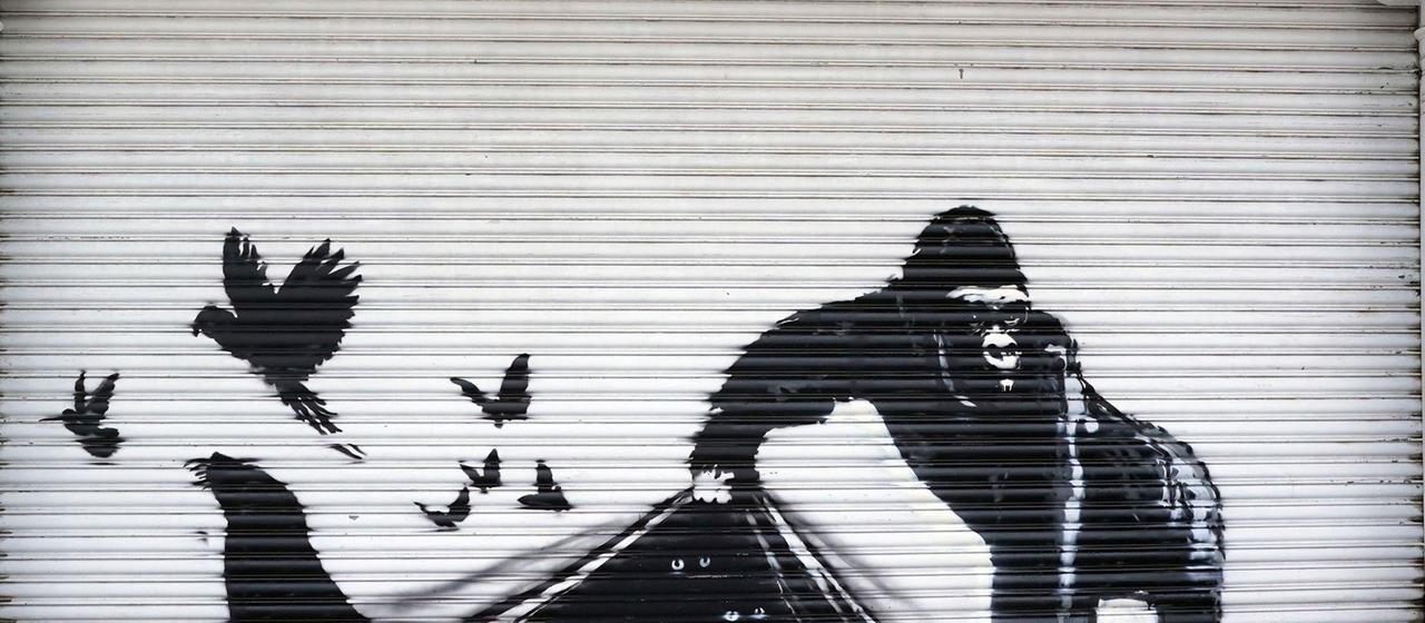 Ein schwarz-weißes Streetart-Gemälde zeigt einen Gorilla, der Tiere, unter anderem eine Robbe und Vögel frei lässt