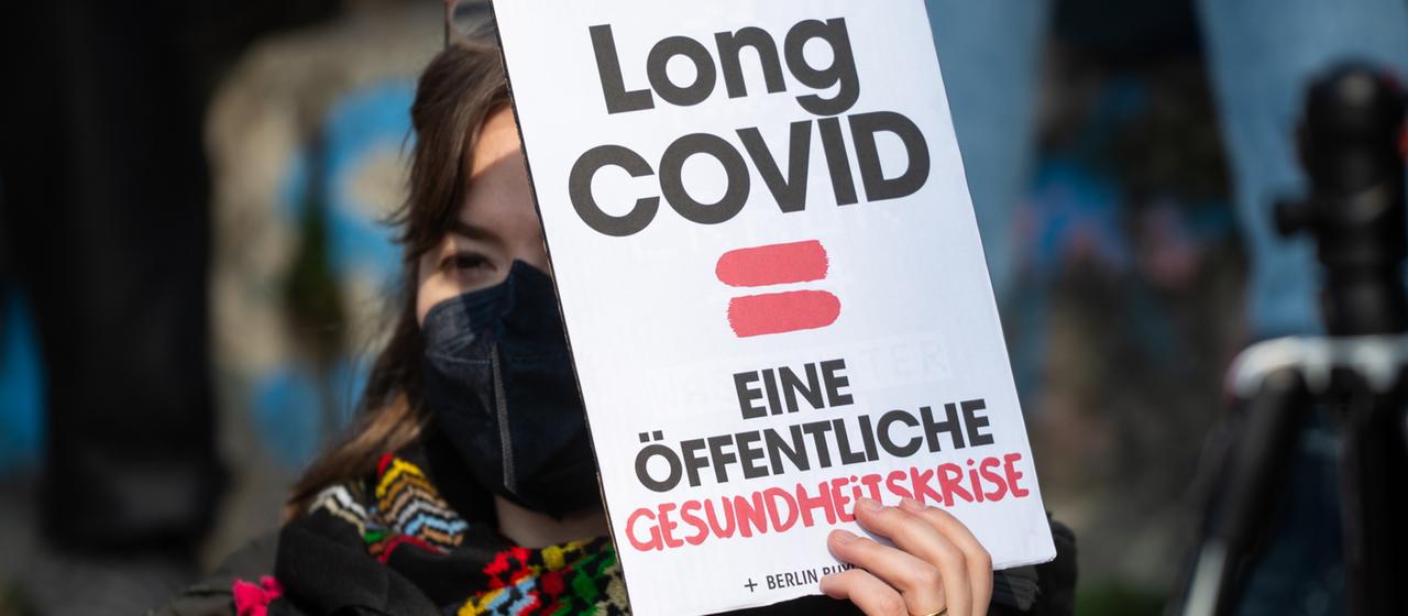 Eine Frau hält ein Plakat mit der Aufschrift 