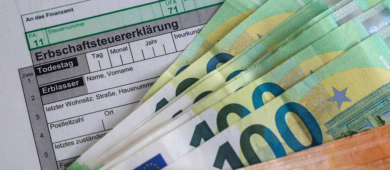  Auf einem Bogen zur Erbschaftsteuererklärung liegen Geldscheine.