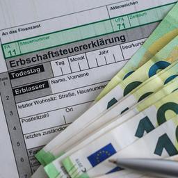  Auf einem Bogen zur Erbschaftsteuererklärung liegen Geldscheine.