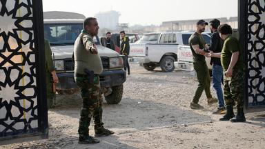 Mitglieder einer irakischen schiitischen militanten Gruppe stehen vor dem Hauptquartier der Popular Mobilization Force, nachdem es von einem Luftangriff getroffen wurde.