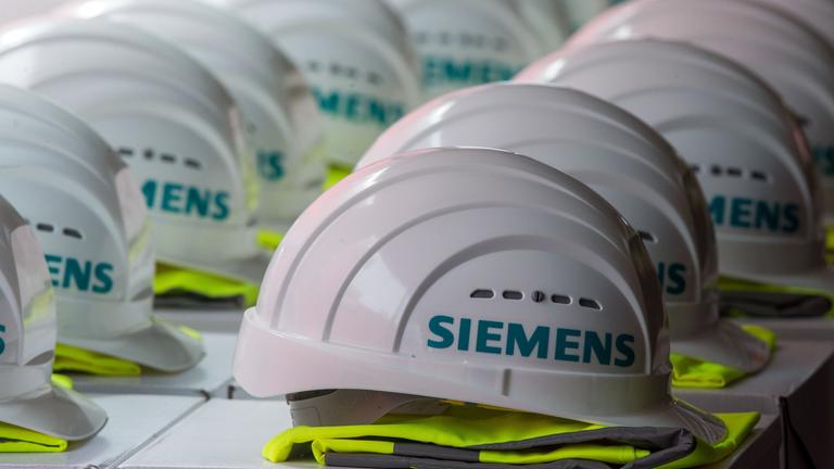 Bauhelme mit dem Logo des Siemens-Konzerns liegen auf einem langen Tisch
