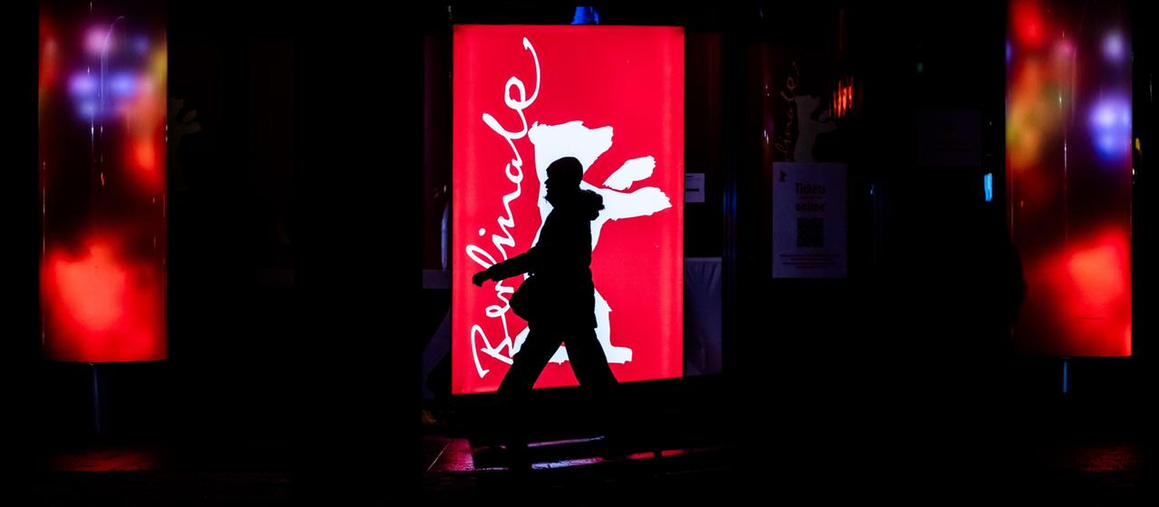 Eine Person geht nahe dem Potsdamer Platz an einer Berlinale-Leuchttafel vorbei.