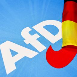Das Logo der AfD neben kleinen Deutschland-Fahnen