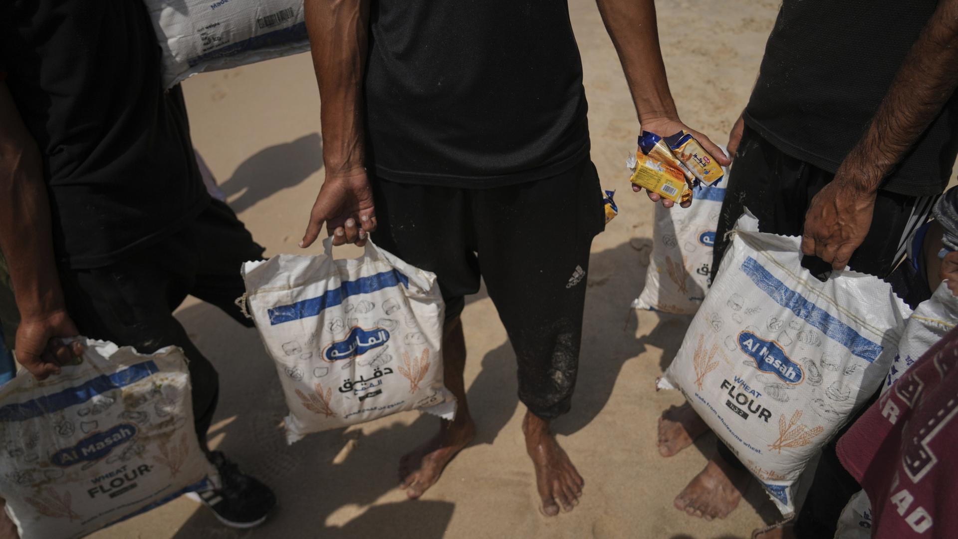 Palästinenser sammeln Mehlsäcke ein, die nach dem Abwurf aus der Luft im Meer gelandet sind. | AP