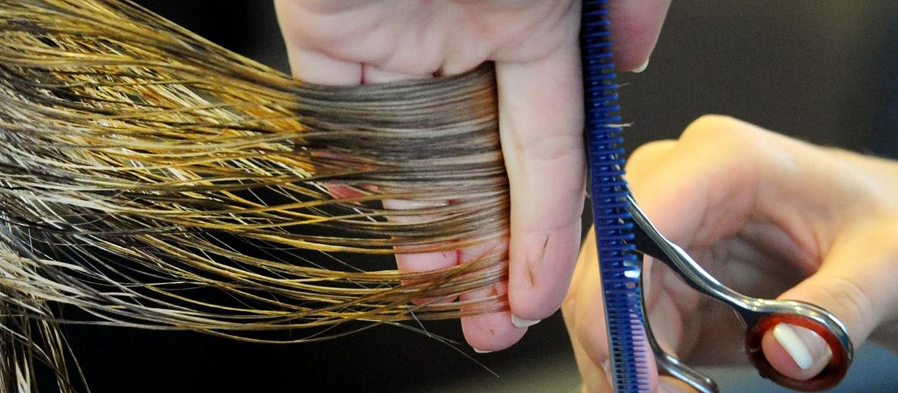 Eine Friseurin schneidet einer Kundin die Haare. | dpa Eine Friseurin schneidet einer Kundin die Haare.