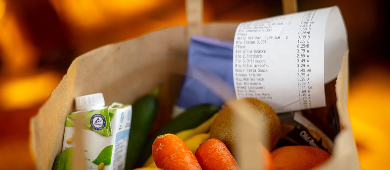 Ein Kassenbon liegt auf den Lebensmitteln in einer Einkaufstüte. 