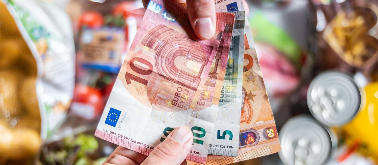 Ein Kunde bezahlt seinen Einkauf im Supermarkt bar mit Euro-Geldscheinen