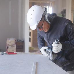 Ein älterer Mann arbeitet am Zuschnitt einer Platte.