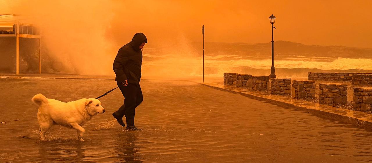 Ein Mann geht mit einem Hund während eines Sandsturms auf der griechischen Insel Kreta.