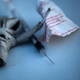 Hilfsmittel zum Drogenkonsum: ein Schnürsenkel, eine Spritze und ein weißes Papiertütchen