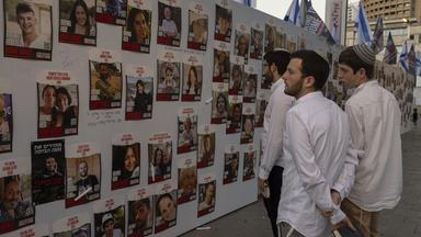 Männer in Tel Aviv schauen auf Fotos von entführten Israelis 