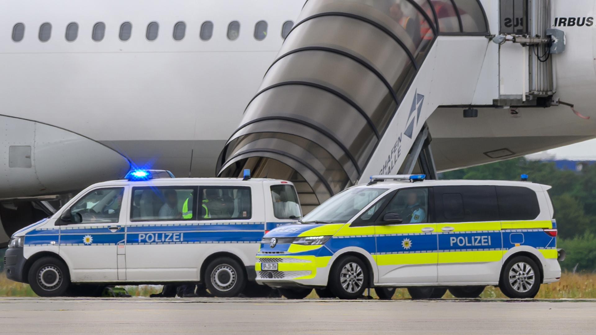 Polizeifahrzeuge stehen vor einem Flugzeug auf dem Flughafen Leipzig/Halle. | dpa