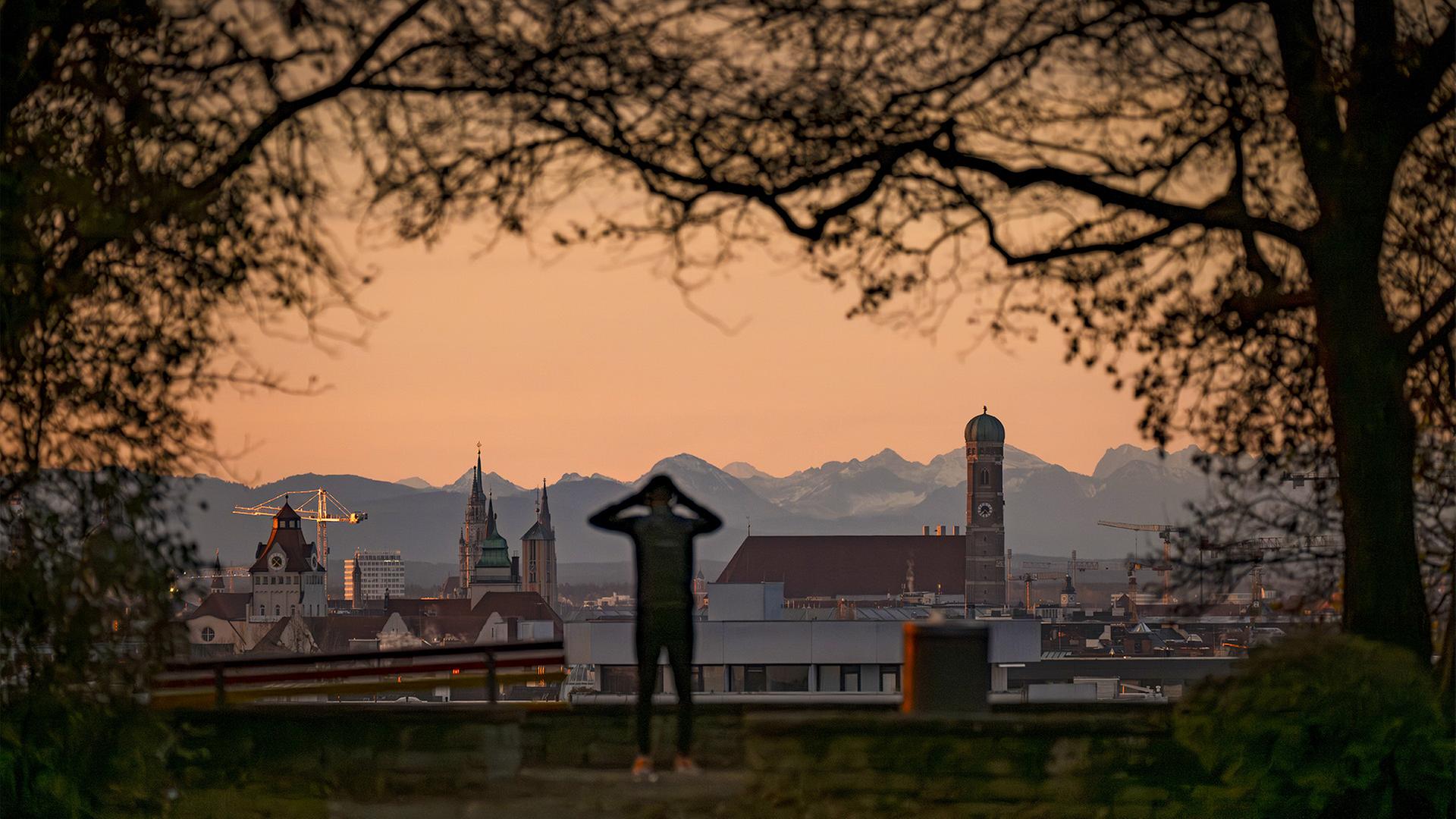Ein Jogger genieÃt am frÃ¼hen Morgen die Aussicht auf die mÃ¼nchener Frauenkirche mit den Alpen im Hintergrund. | dpa
