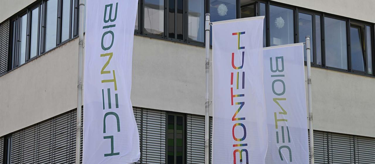 Fahnen mit dem Unternehmenslogo vor einem Laborgebäude von Biontech.