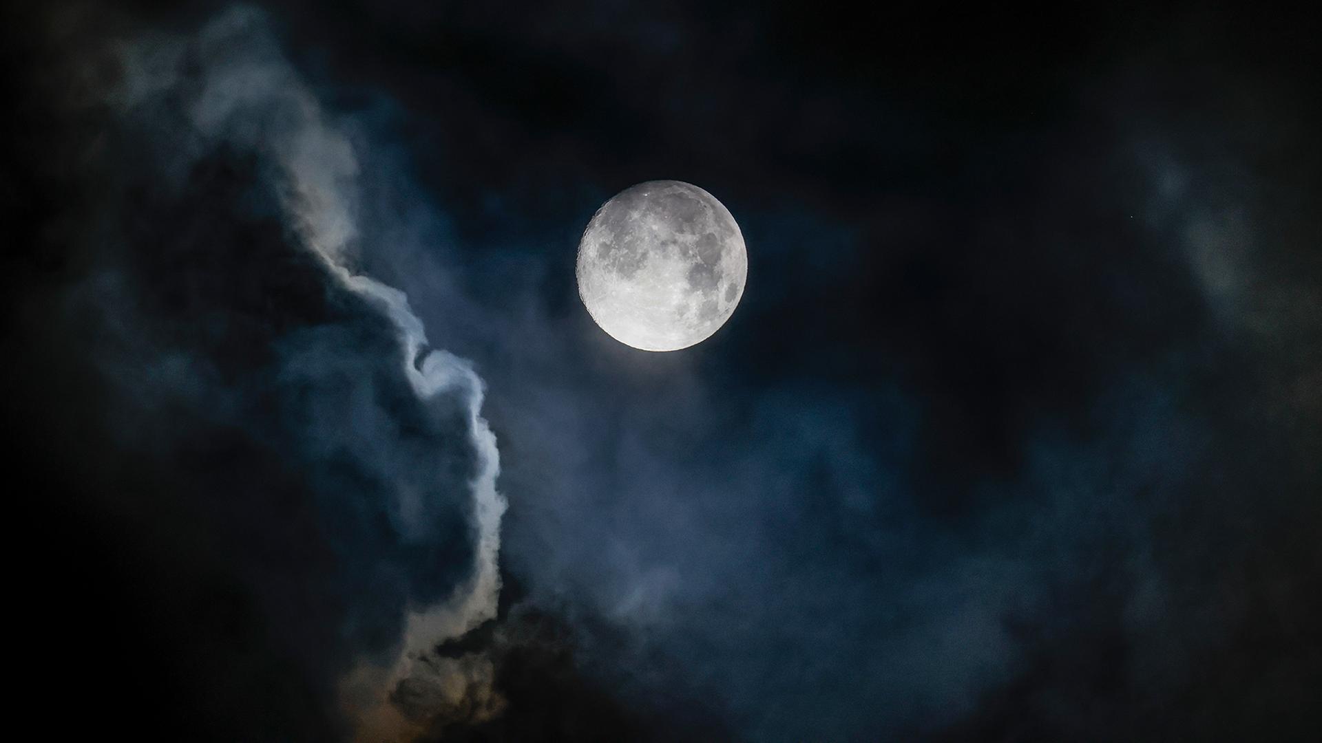 Der fast vollständig sichtbare, zunehmende Mond ist am frühen Morgen in Königswinter (Nordrhein-Westfalen) am bewölkten Himmel zu sehen. | dpa