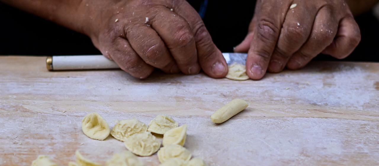 Eine Frau bereitet traditionelle Orecchiette-Nudeln zu.
