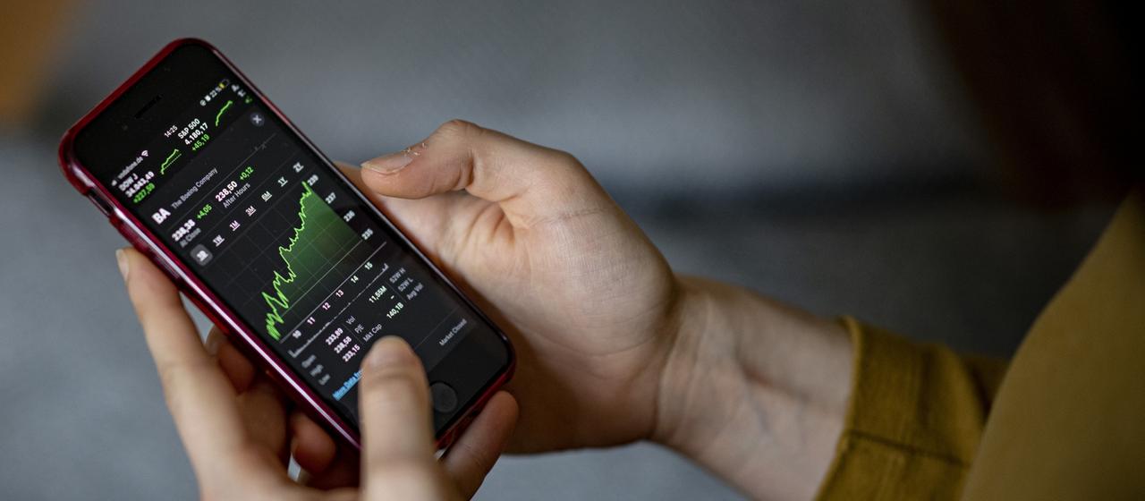 Eine Person schaut sich Aktienkurse auf dem Smartphone an.