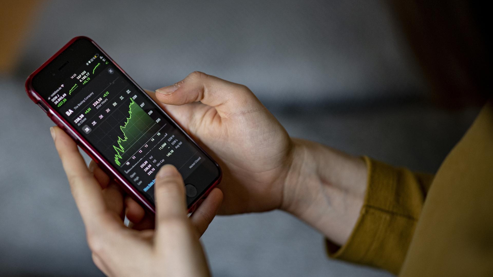 Eine Person schaut sich Aktienkurse auf dem Smartphone an. | dpa
