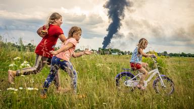 Kinder spielen vor Rauchschwaden in der Ukraine.