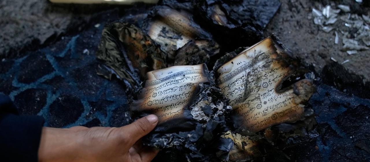 Ein Mann hält einen verbrannten Koran in der Hand