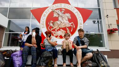 Vor einer Verteilstation für Hilfsgüter in Belgorod (Russland) sitzen Menschen.