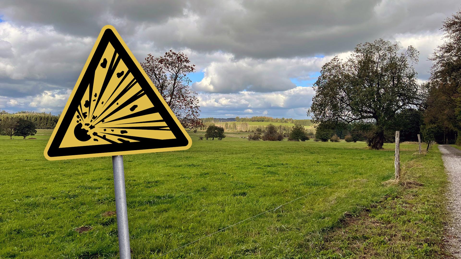 Das ist eine Collage. Im Hintergrund ist ein Foto einer grünen Wiese mit einigen Bäumen und einem dramatischen Himmel zu sehen. Im Vordergrund steht ein Schild: Achtung Explosionsgefahr. | Eva Roessler (hr); AdobeStock | eyewave; Collage: hessenschau.de