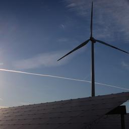 Windrad und Sonne hinter einer Solaranlage