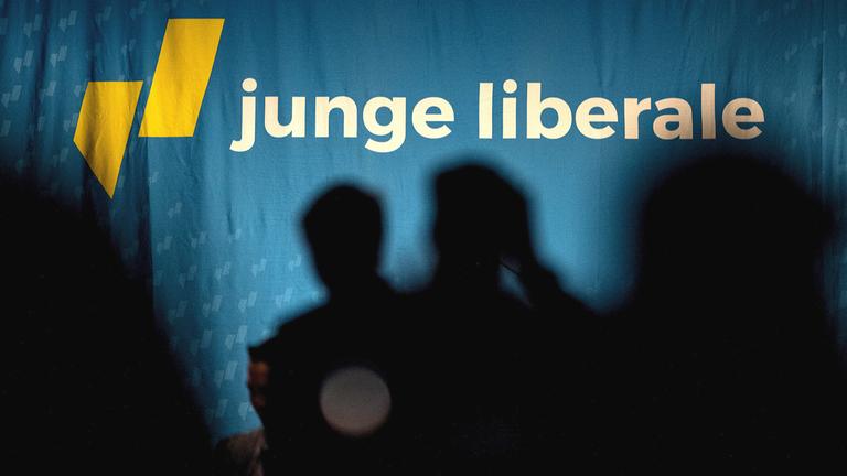 Silhouetten von Delegierte stehen vor dem Schriftzug der Jungen Liberalen.