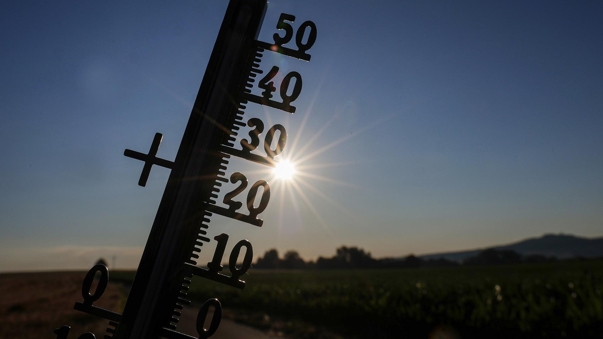 Die Sonne scheint hinter einem Thermometer in Baden-Württemberg. | dpa