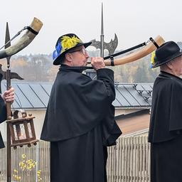 Drei Männer in Nachtwächtergewand stoßen ins Horn.