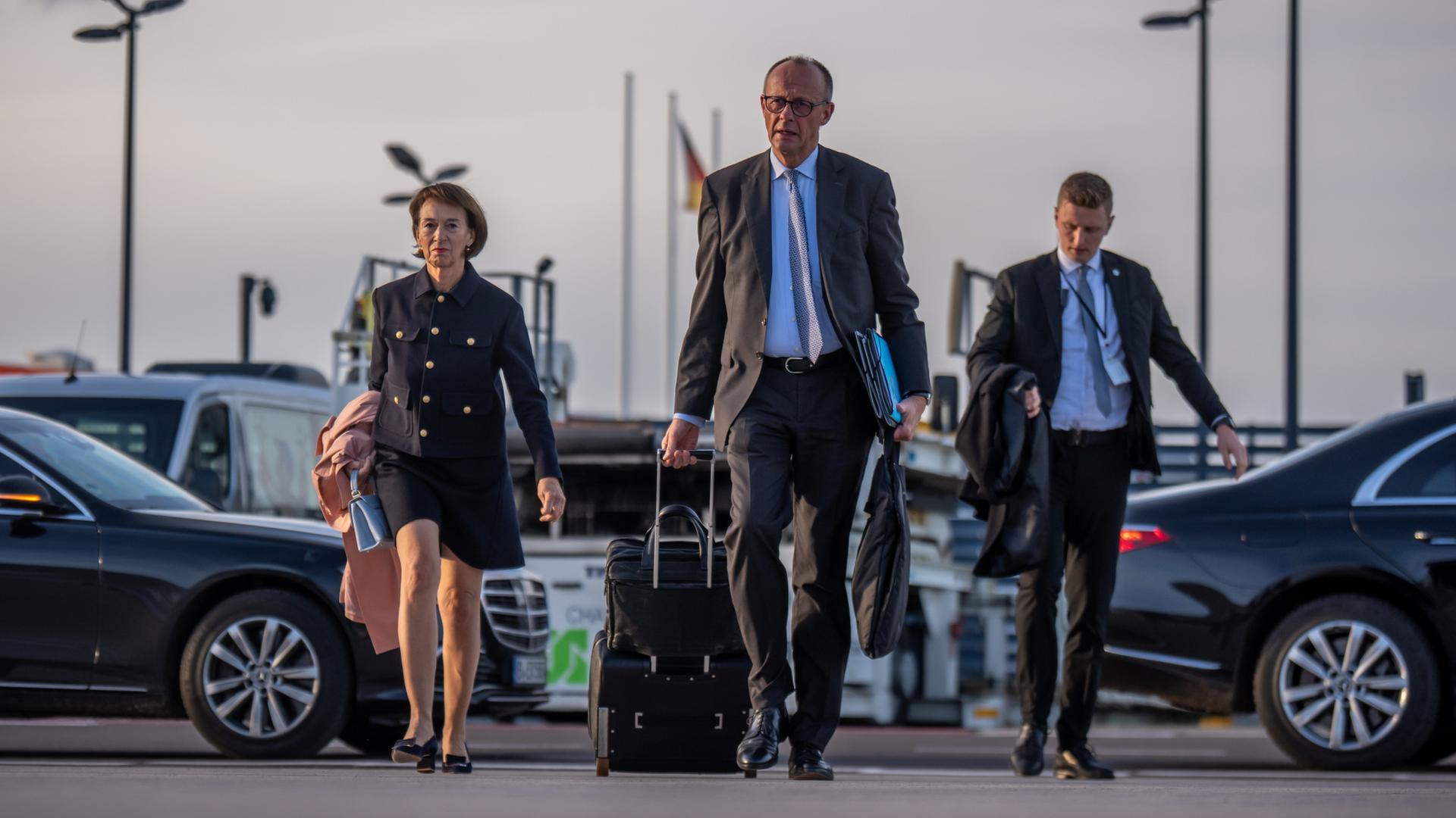 Bundeskanzler Friedrich Merz (CDU, M) geht neben seiner Frau Charlotte zu einem Flugzeug der Flugbereitschaft, um in die Türkei zu fliegen. | dpa