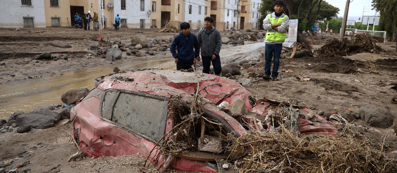 Menschen inspizieren nach Überschwemmungen die Straße, die durch starke Regenfälle zerstört wurde.