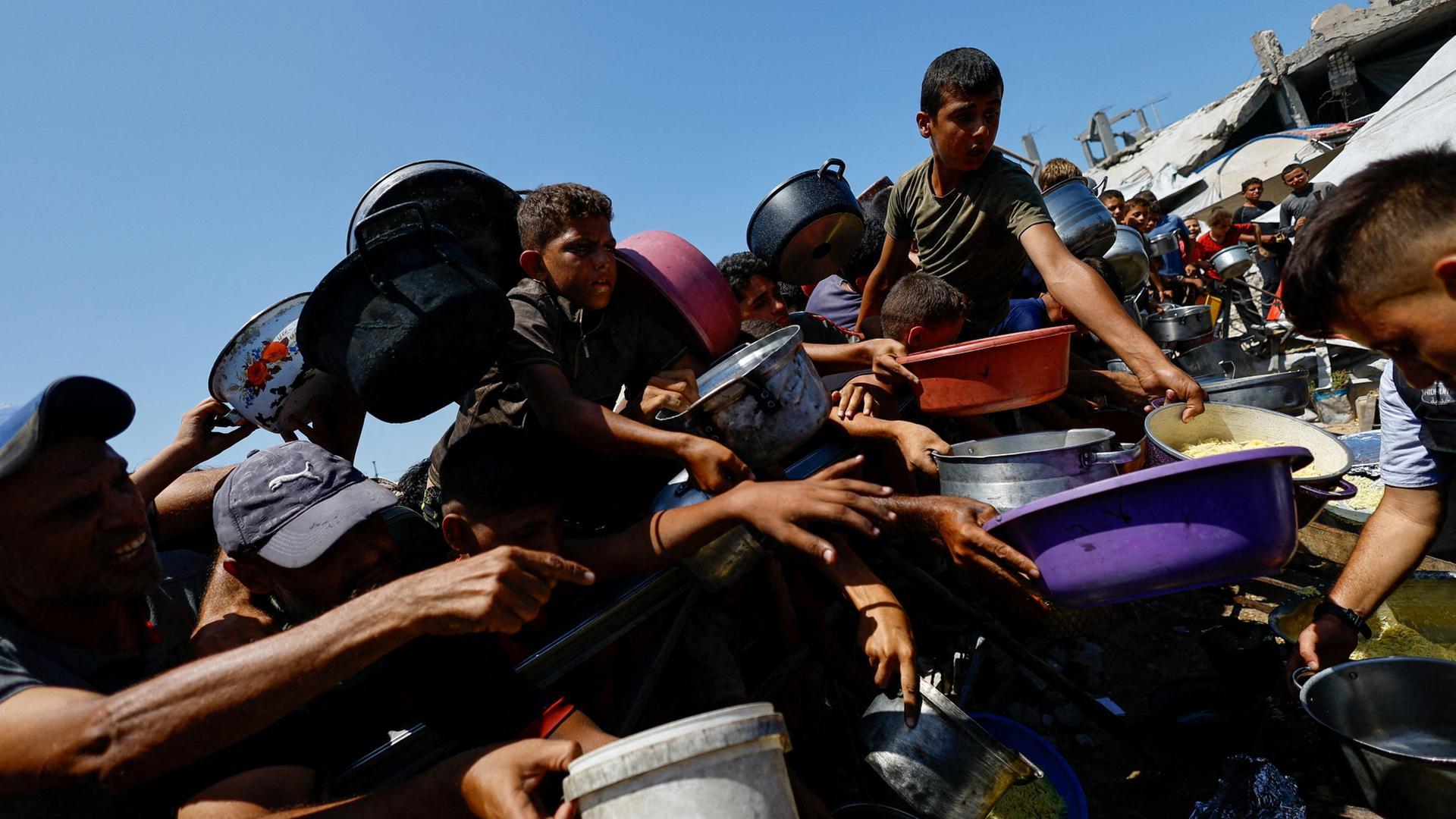 Menschen im Gazastreifen drängen sich mit Schüsseln um eine Essensausgabe. | REUTERS