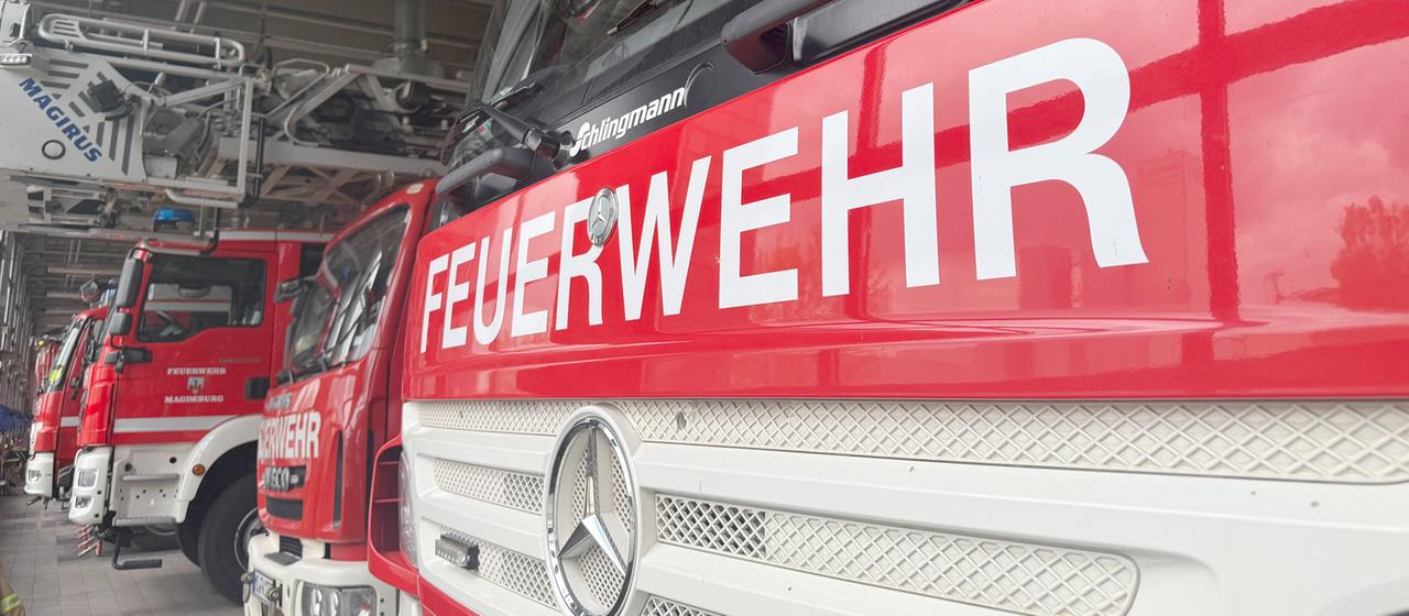 Einsatzwagen der Feuerwehr stehen in einer Halle.