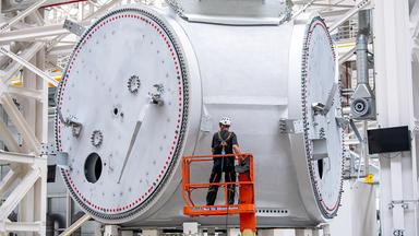 Mitarbeiter auf einer Hebebühne in der Produktionshalle der Offshore-Maschinenhausfertigung von Siemens Gamesa.