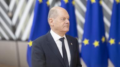 Olaf Scholz steht vor Flaggen der Europäischen Union.