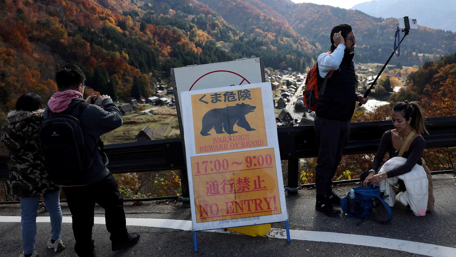 Besucher machen Erinnerungsfotos neben einem Warnschild für Bären in Shirakawa-go, Japan. | REUTERS