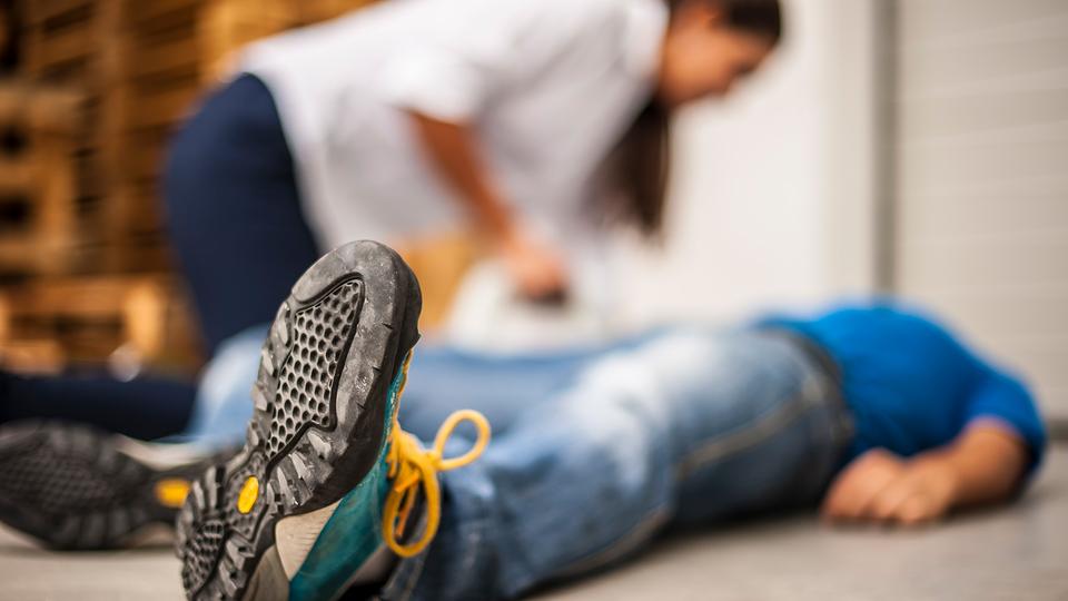 Eine Frau beugt sich über einen Mann, der auf dem Boden liegt.