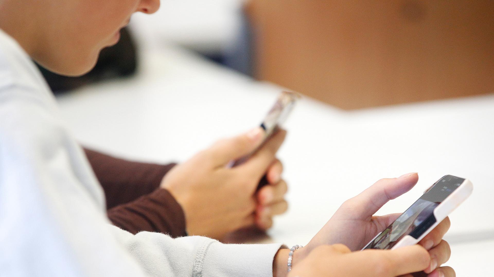 Personen schauen auf Bildschirme von Mobiltelefonen. | dpa