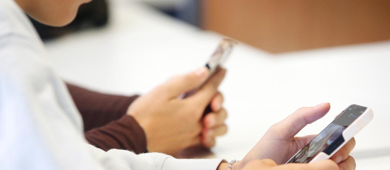 Schüler schauen während des Unterrichts auf ihre Handys.
