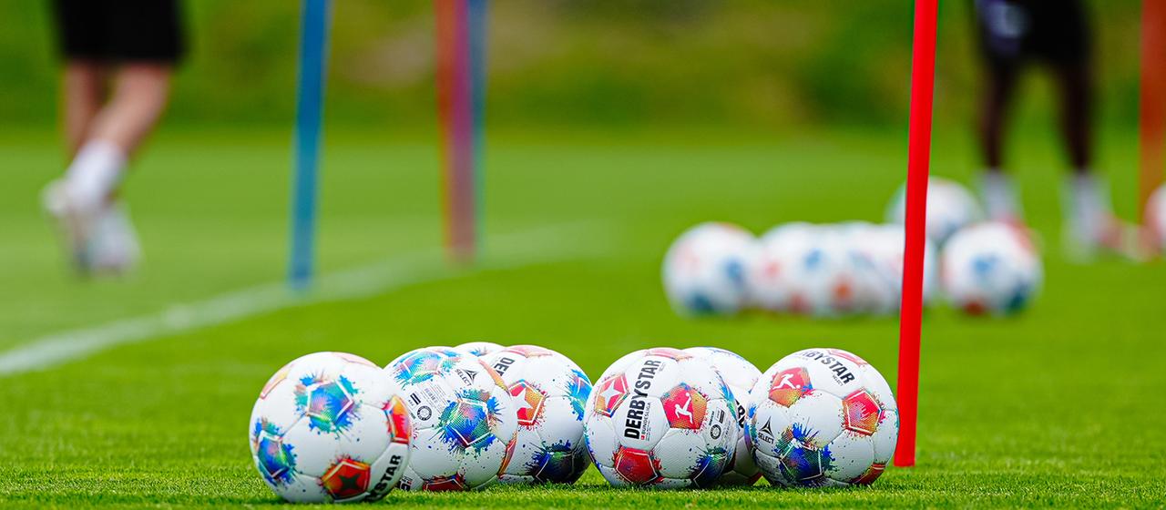 Fußbälle liegen auf einem Trainingsplatz.