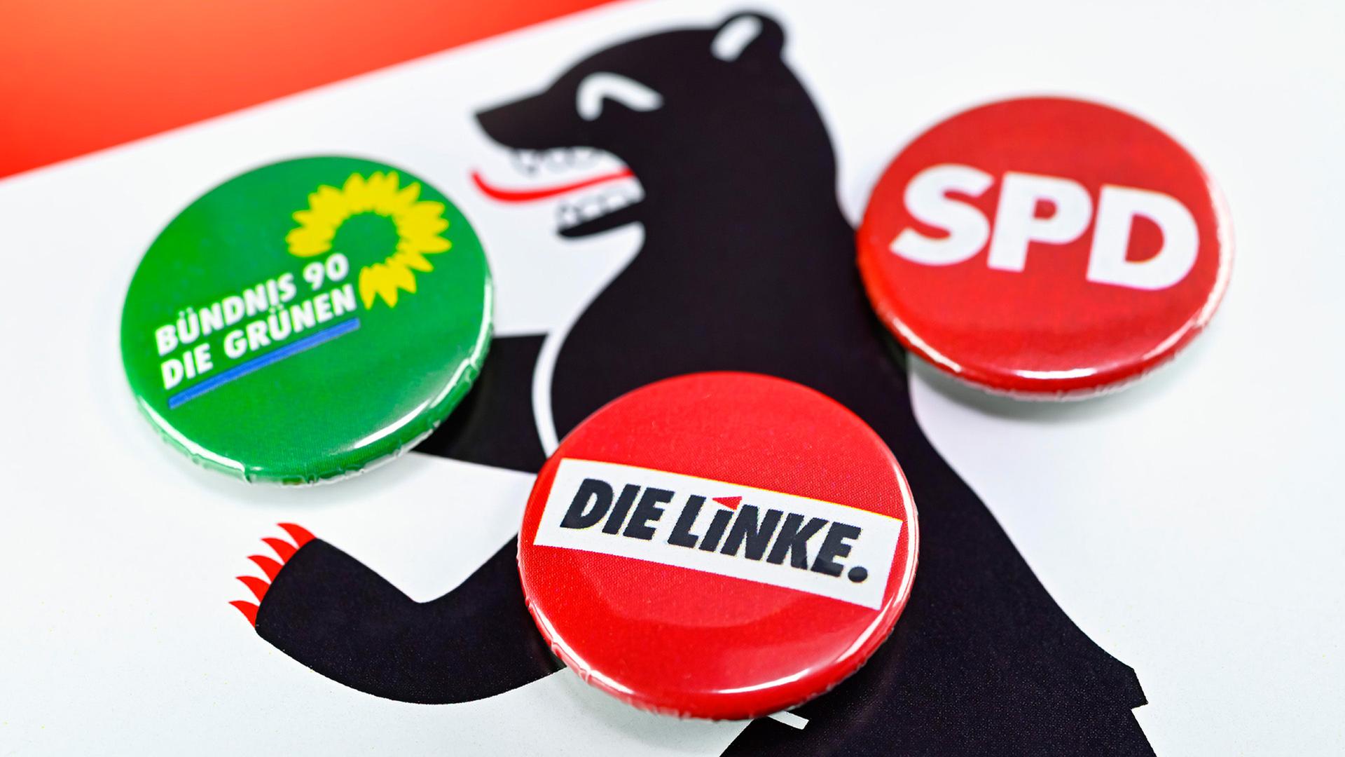Parteianstecker von Die Linke, SPD und Die Grünen auf Wappen von Berlin. (Quelle: dpa/Christian Ohde) | dpa/Christian Ohde