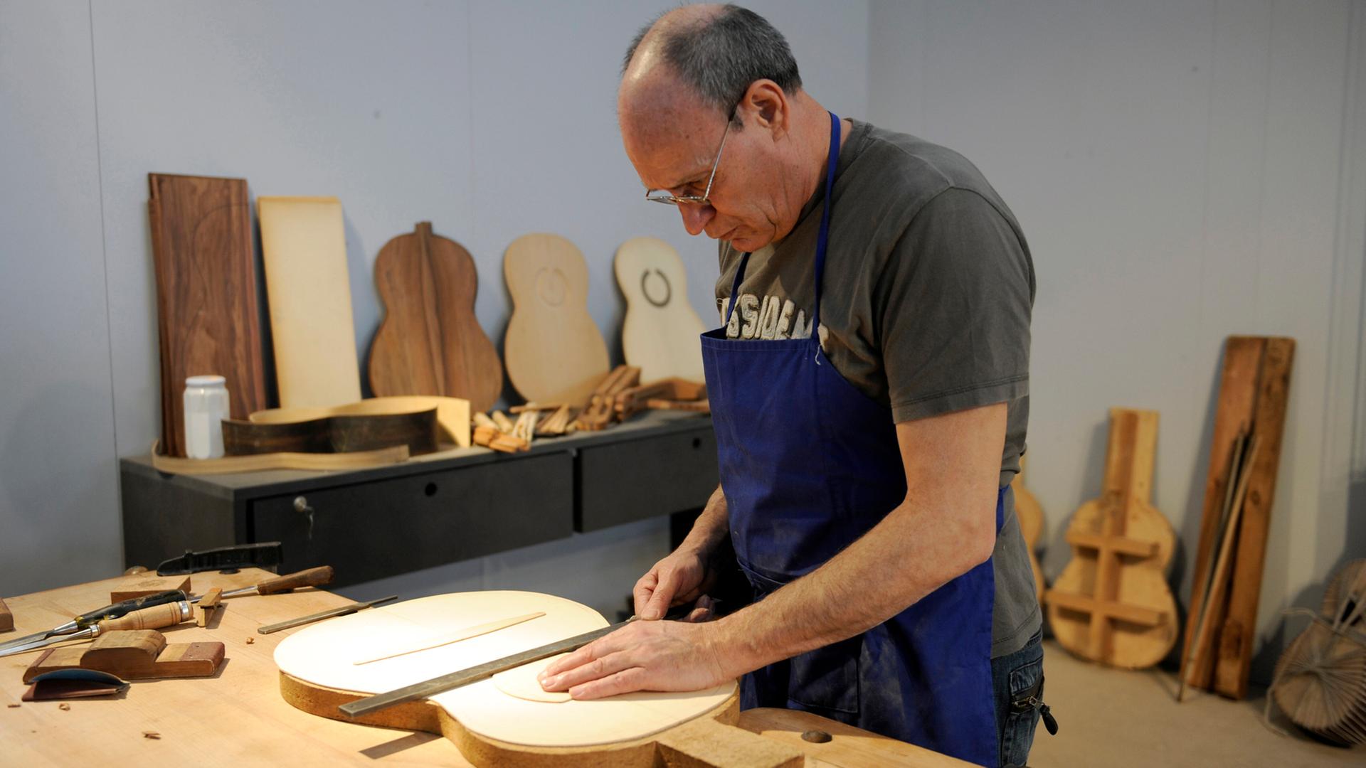 Ein Rentner baut eine Gitarre in einer Werkstatt. | picture alliance / SvenSimon