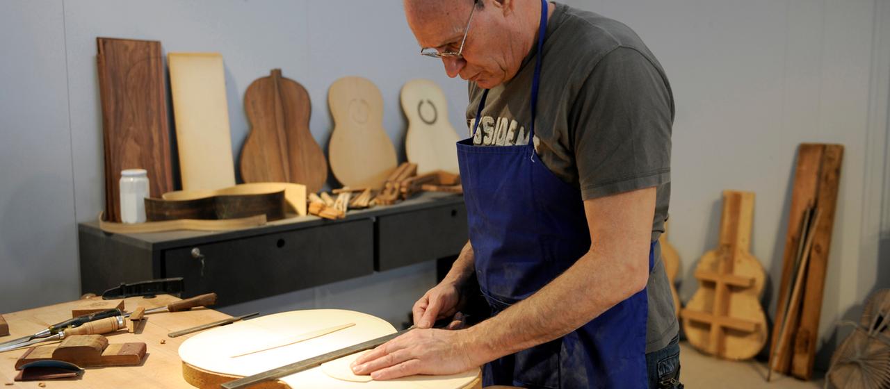 Ein Rentner baut eine Gitarre in einer Werkstatt.