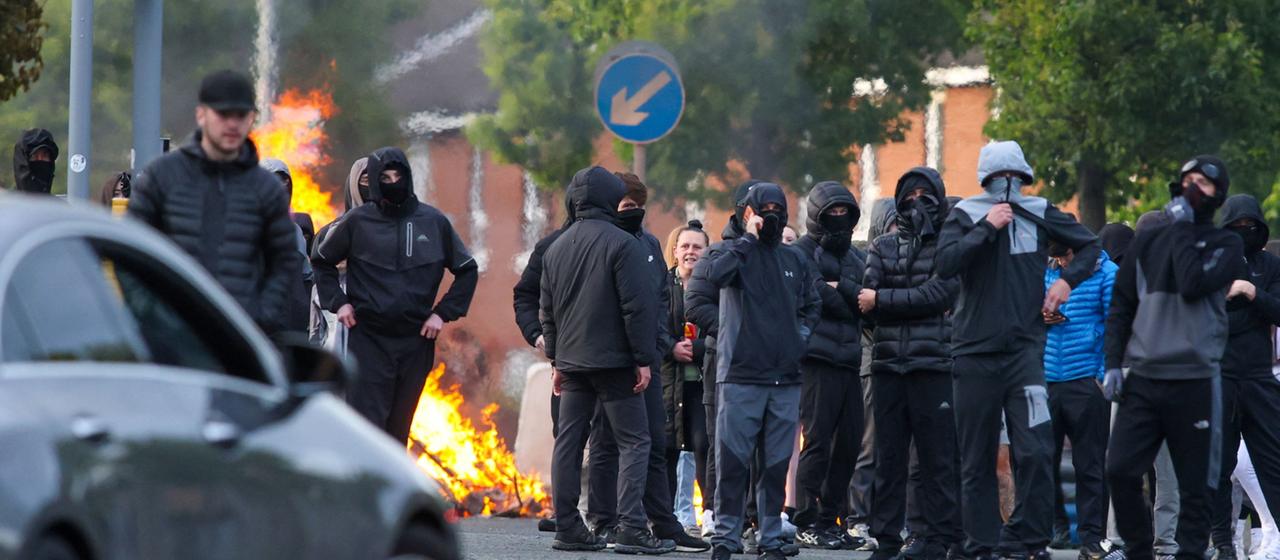 Maskierte Jugendliche vor einer brennenden Barrikade in Belfast