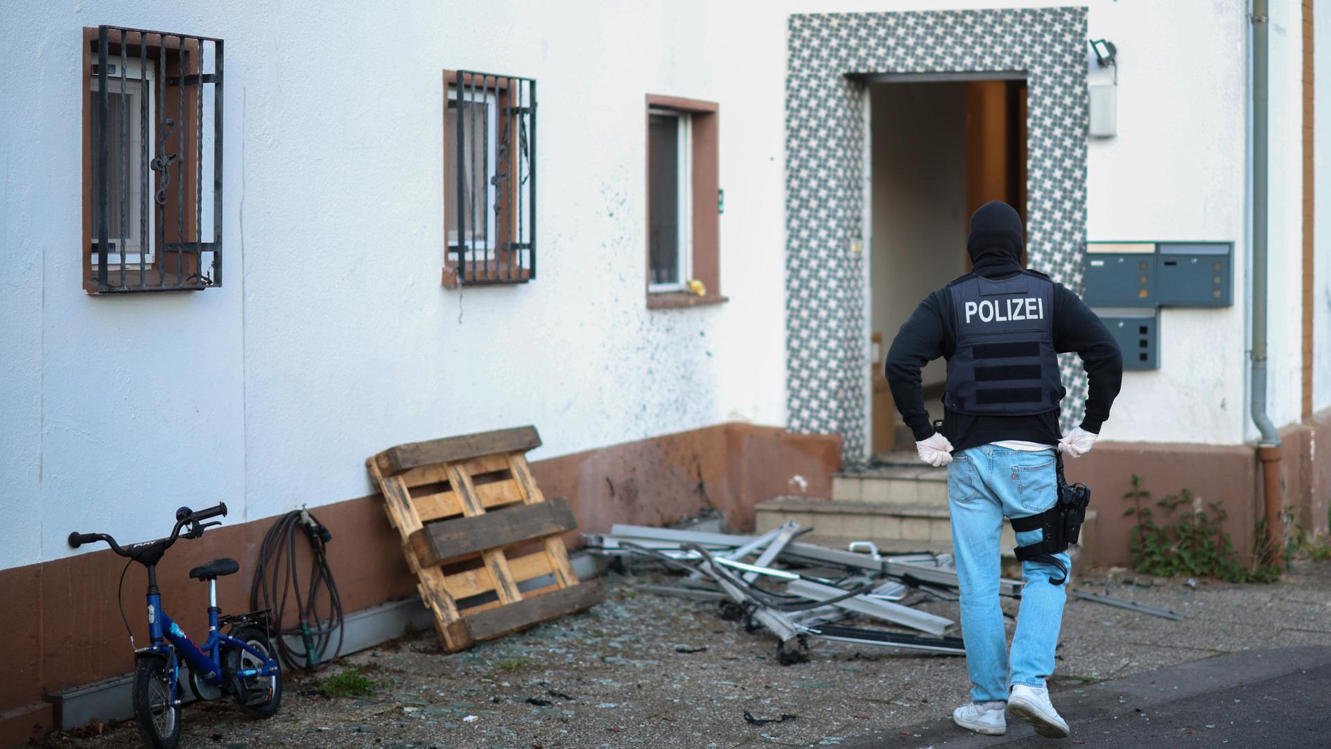 Ein Polizeibeamter steht im Rahmen einer Razzia gegen die Hells Angels vor einem Wohnhaus in Langenfeld | dpa / Christoph Reichwein